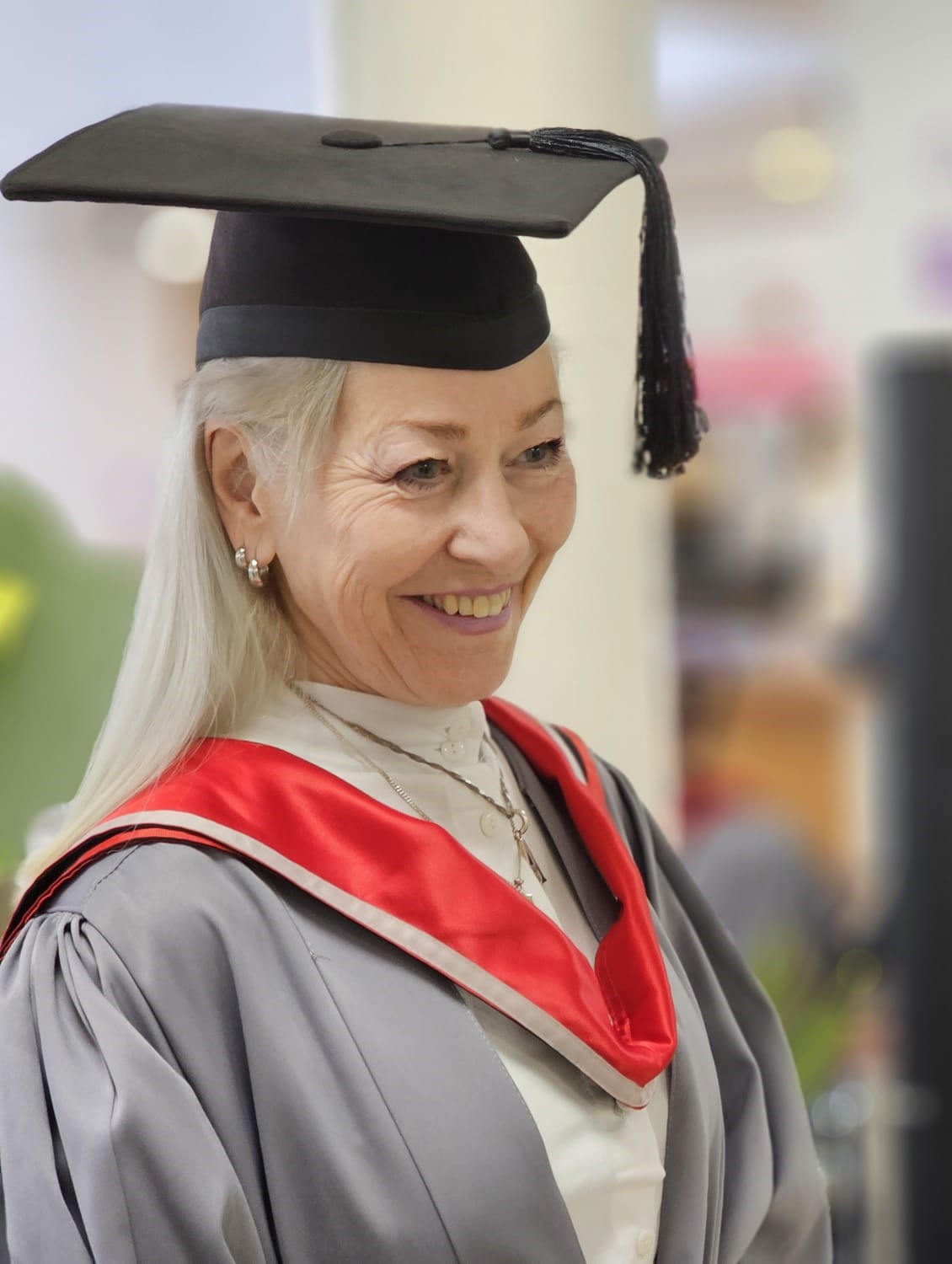 A proessional woman wearing graduation robes and mortar hat.